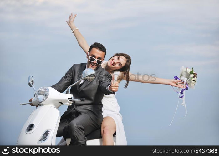 wedding sce of bride and groom just married couple on the beach ride white scooter and have fun