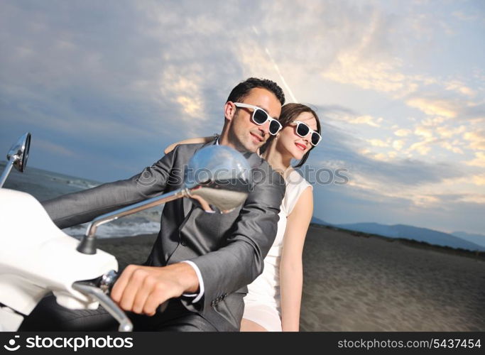 wedding sce of bride and groom just married couple on the beach ride white scooter and have fun