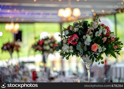 Wedding table decoration. Beautiful bouquet of flowers in vase on the table. Bouquet of flowers, setting on the festive table in restaurant.