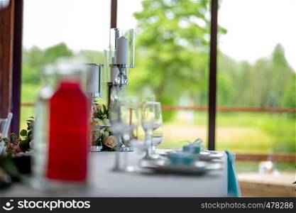 Wedding table decoration. Candlestick with candles and dishes on the table. Candles in candlestick setting on the festive table in restaurant. Focus on candles.