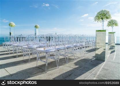 Wedding venue on the hill, white chairs, flowers, floral decoration, ocean background