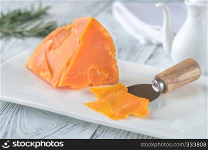 Wedge of Mimolette cheese on white plate