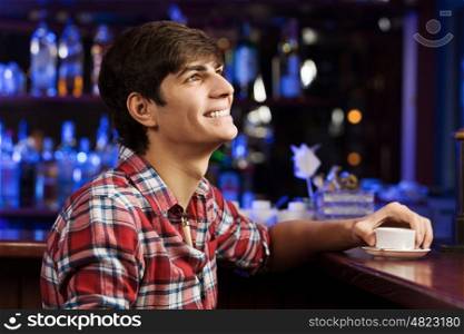 Weekend evening. Young handsome man in casual sitting at bar