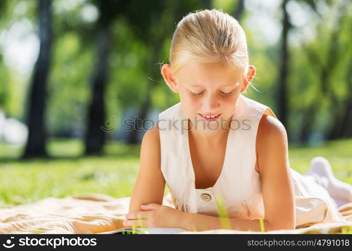 Weekend in park. Little cute girl in summer park reading book