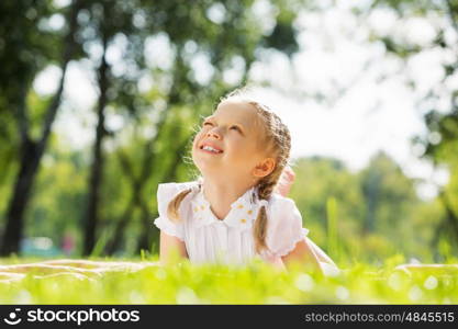 Weekend in park. Little cute girl in summer park reading book