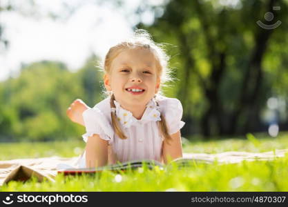 Weekend in park. Little cute girl in summer park reading book