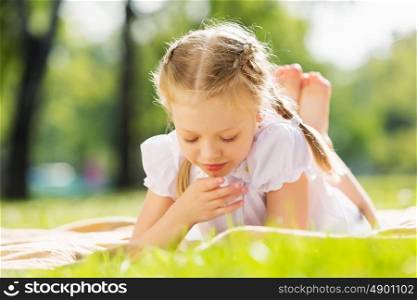 Weekend in park. Little cute girl in summer park reading book