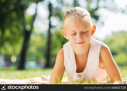 Weekend in park. Little cute girl in summer park reading book