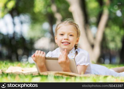 Weekend in park. Little cute girl in summer park reading book