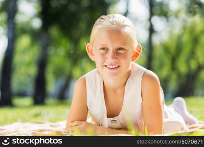 Weekend in park. Little cute girl in summer park reading book