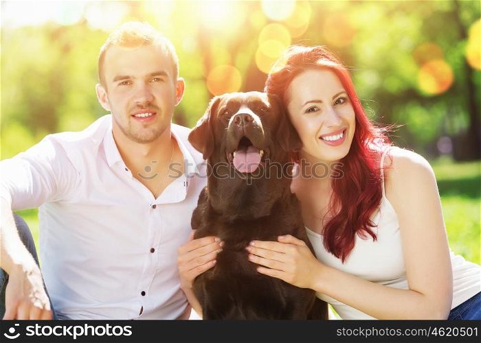 Weekend in park. Young couple with labrador having fun and enjoying the beautiful nature