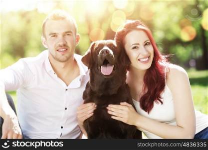 Weekend in park. Young couple with labrador having fun and enjoying the beautiful nature