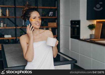 Weekend morning: Woman applies eye patches, relaxes at home, talks on phone. Hispanic girl in towel, modern interior.