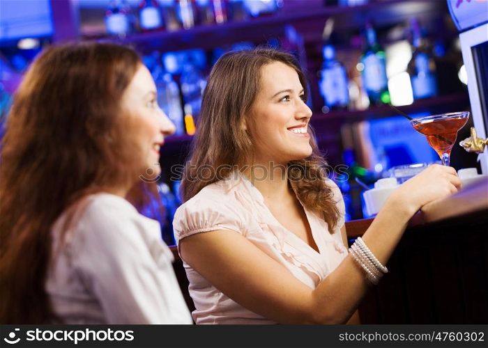 Weekend party. Two young pretty women a bar drinking cocktails