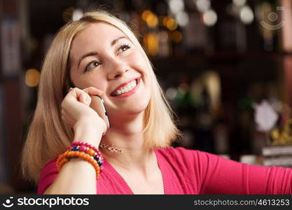 Weekend party. Young attractive lady at bar talking on phone