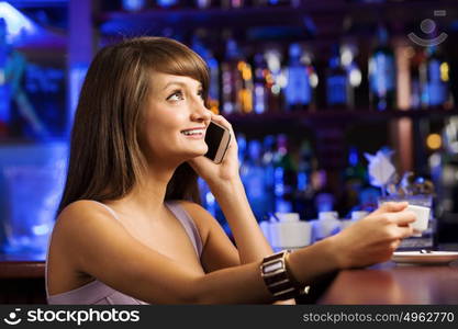 Weekend party. Young attractive lady at bar talking on phone