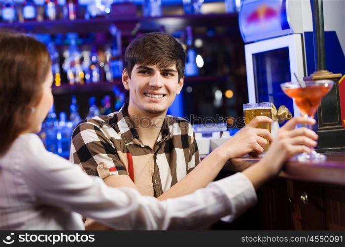 Weekend party. Young couple in bar having drinks and talking