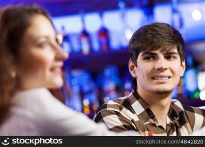 Weekend party. Young couple in bar having drinks and talking