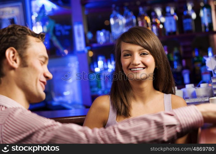 Weekend party. Young couple in bar having drinks and talking