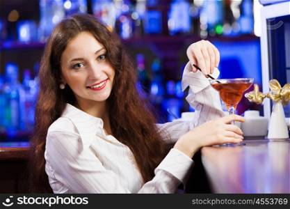 Weekend party. Young pretty girl at bar drinking cocktail