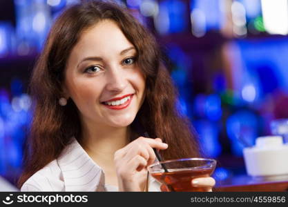 Weekend party. Young pretty girl at bar drinking cocktail