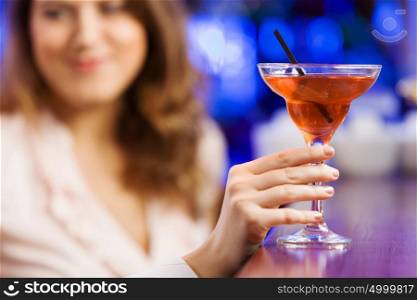 Weekend party. Young pretty girl at bar drinking cocktail