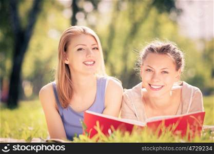 Weekend picnic. two young pretty woman in summer park reading book