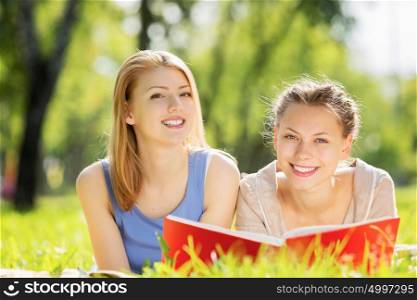 Weekend picnic. Young pretty girls in summer park reading book