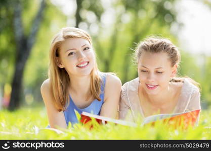 Weekend picnic. Young pretty girls in summer park reading book