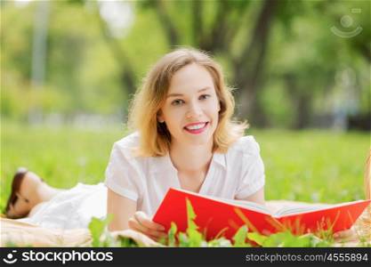 Weekend picnic. Young pretty woman in summer park reading book