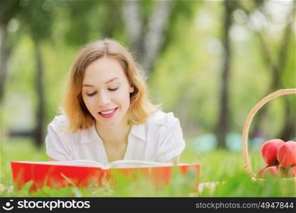 Weekend picnic. Young pretty woman in summer park reading book