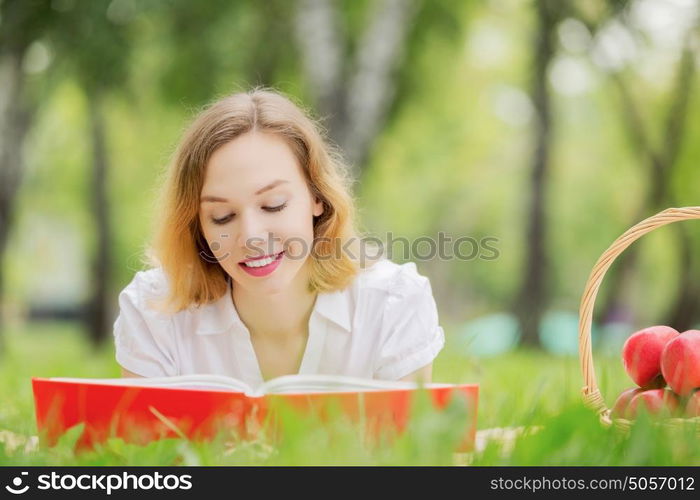 Weekend picnic. Young pretty woman in summer park reading book