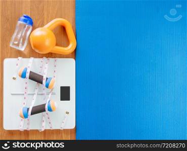 weight loss and physical activity concept from weight scale digital with measure tape for check body shape and workout equipment on a wooden floor.