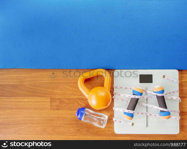 weight loss and physical activity concept from weight scale digital with measure tape for check body shape and workout equipment on a wooden floor.