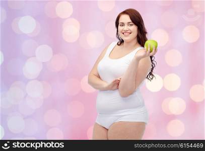 weight loss, diet, slimming, healthy eating and people concept - happy young plus size woman in underwear with green apple over pink holidays lights background