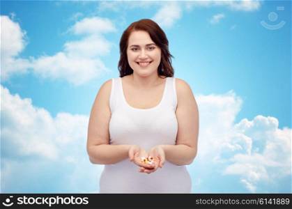 weight loss, diet, slimming, medicine and people concept - happy plus size woman in underwear with pills over blue sky and clouds background