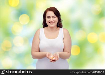 weight loss, diet, slimming, medicine and people concept - happy plus size woman in underwear with pills over green lights background