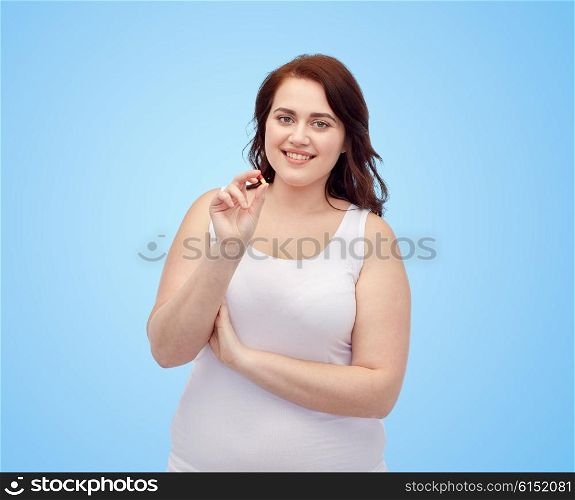 weight loss, diet, slimming, medicine and people concept - happy plus size woman in underwear with pill over blue background