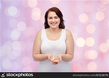 weight loss, diet, slimming, medicine and people concept - happy plus size woman in underwear with pills over pink holidays lights background