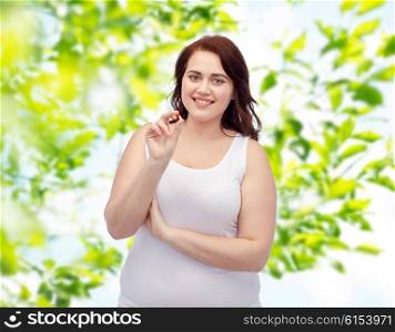 weight loss, diet, slimming, medicine and people concept - happy plus size woman in underwear with pill over green natural background