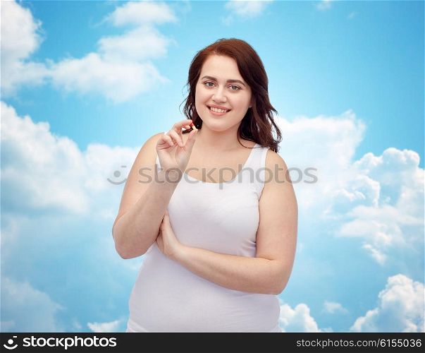 weight loss, diet, slimming, medicine and people concept - happy plus size woman in underwear with pill over blue sky and clouds background
