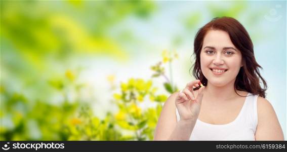 weight loss, diet, slimming, medicine and people concept - happy plus size woman in underwear with pill over green natural herbal background