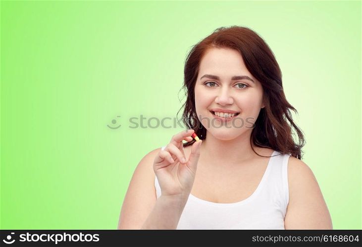 weight loss, diet, slimming, medicine and people concept - happy plus size woman in underwear with pill over green natural background