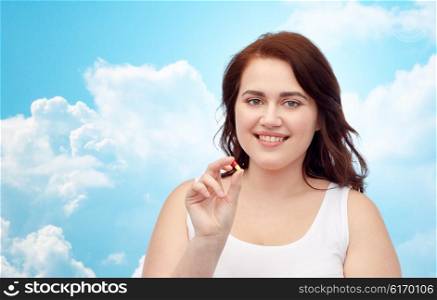 weight loss, diet, slimming, medicine and people concept - happy plus size woman in underwear with pill over blue sky and clouds background