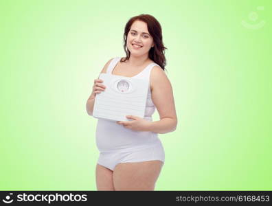 weight loss, diet, slimming, plus size and people concept - happy young plus size woman in underwear holding scales over green natural background