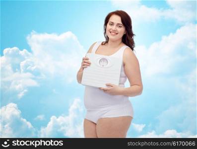 weight loss, diet, slimming, plus size and people concept - happy young plus size woman in underwear holding scales over blue sky and clouds background