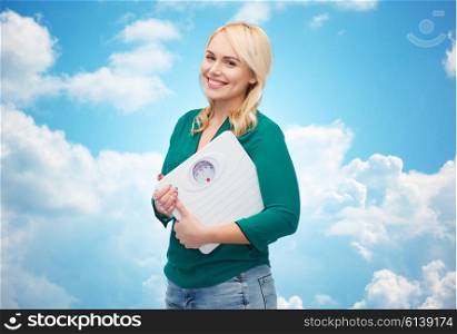 weight loss, diet, slimming, plus size and people concept - smiling young woman holding scales over blue sky and clouds background