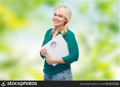 weight loss, diet, slimming, plus size and people concept - smiling young woman holding scales over green natural background