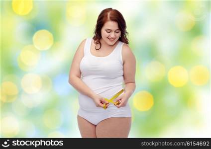 weight loss, diet, slimming, size and people concept - happy young plus size woman in underwear measuring tape over green lights background
