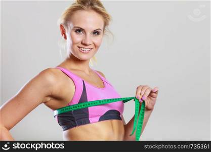 Weight loss, slim body, healthy lifestyle concept. Fit fitness woman in sport bra measuring her chest breasts with green measure tape. Fit woman measuring her chest breasts with tape measure